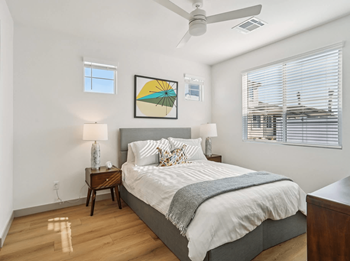 A bedroom with a bed, nightstand, and a ceiling fan.